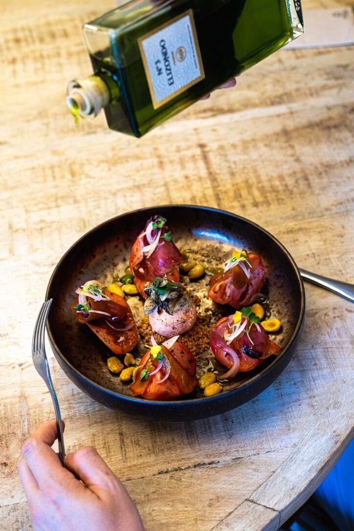 Tapa oscura con salsa y flor comestible
