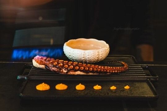 Pulpo a la brasa sobre parrilla con fuego vivo